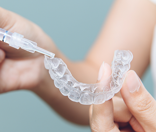 Person placing teeth whitening gel in a tray
