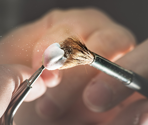 Close up of a small brush dusting off a dental crown