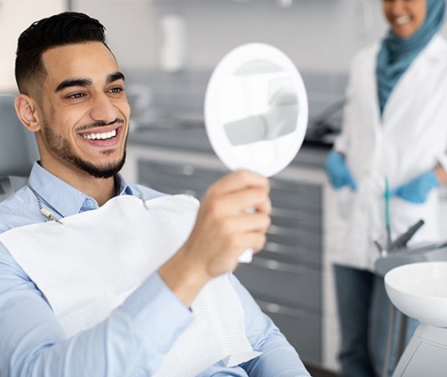 Large shiny model tooth next to dollar bills on light blue surface