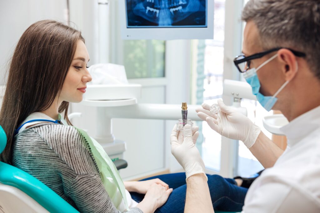 Dentist showing sample implant to patient in dental chair