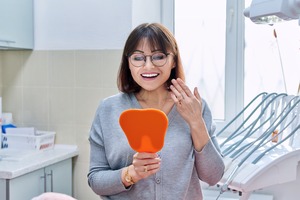 Woman with glasses looking at smile in mirror